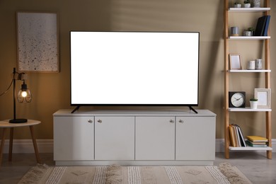 Image of Tv set with white screen on stand in room. Mockup for design