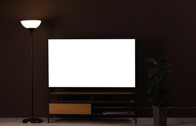 Image of Tv set with white screen on stand in room. Mockup for design