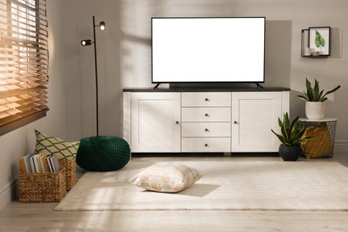 Image of Tv set with white screen on stand in room. Mockup for design