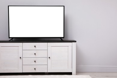 Image of Tv set with white screen on stand in room. Mockup for design