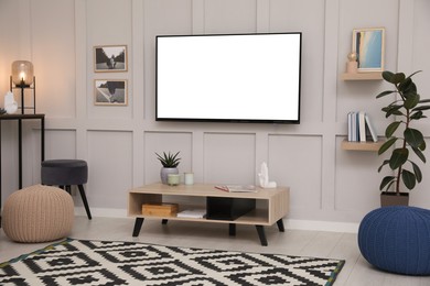 Tv set with white screen mounted on wall in room. Mockup for design