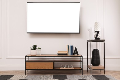 Image of Tv set with white screen mounted on wall in room. Mockup for design