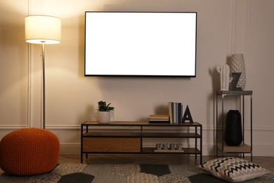 Image of Tv set with white screen mounted on wall in room. Mockup for design