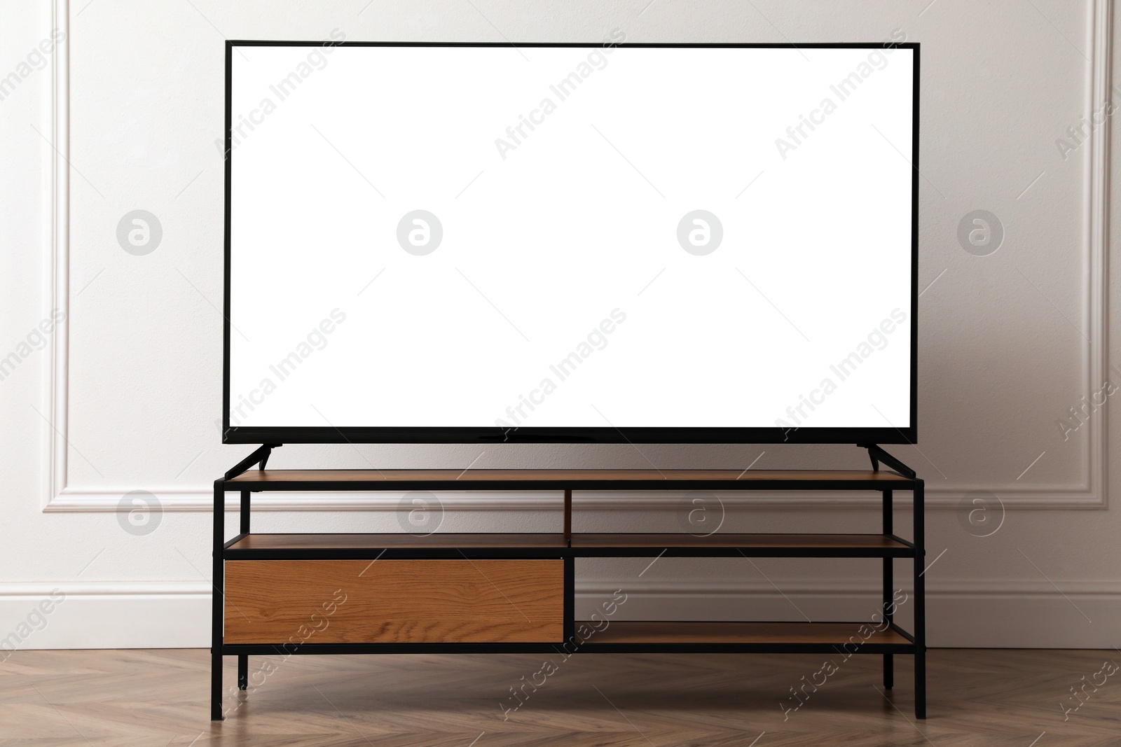 Image of Tv set with white screen on stand in room. Mockup for design