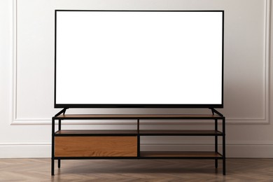 Image of Tv set with white screen on stand in room. Mockup for design