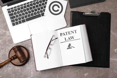 Image of License. Patent law book, laptop, paper with copyright symbol and judge's gavel on grey table, flat lay