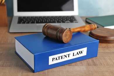 Image of License. Patent law book,judge's gavel and laptop on wooden table, closeup