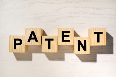 Image of License. Word Patent made of wooden cubes with letters on white table, top view