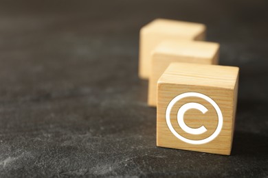 Image of License. Wooden cube with copyright symbol on grey textured table, closeup. Space for text