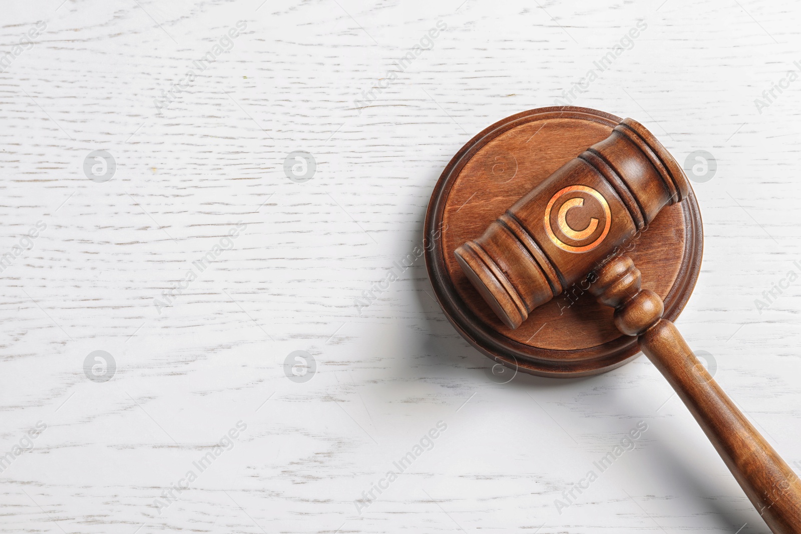 Image of License. Judge's gavel with copyright symbol on white wooden table, top view. Space for text