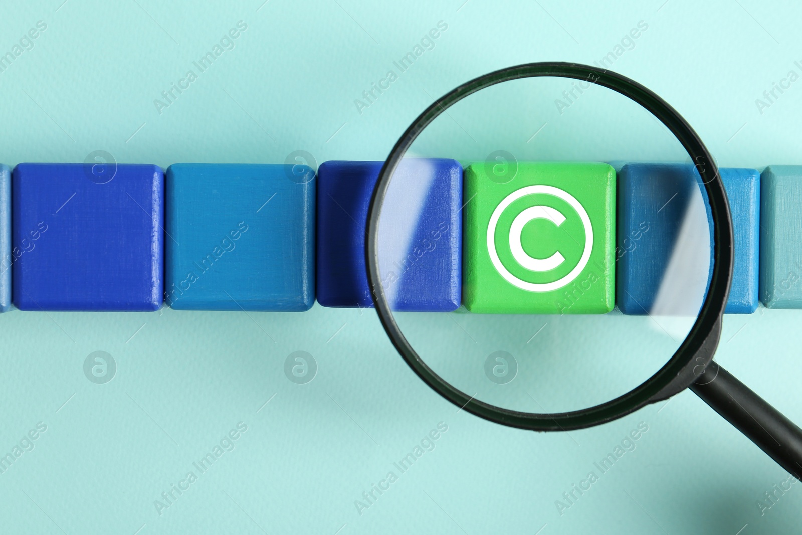 Image of License. One green cube with copyright symbol among others on turquoise table, top view through magnifying glass