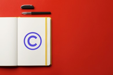 Image of License. Notebook with copyright symbol and pen on red background, top view