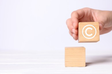 Image of License. Woman holding wooden cube with copyright symbol on white background, closeup. Space for text