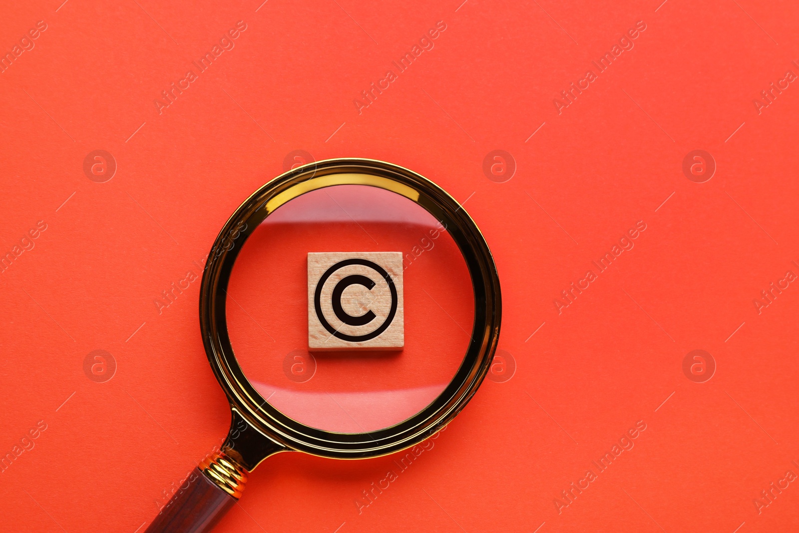 Image of License. Wooden cube with copyright symbol on red background, top view through magnifying glass