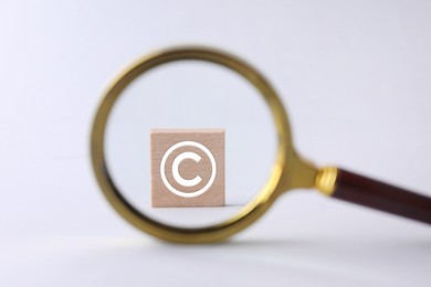 Image of License. Wooden cube with copyright symbol on white background, view through magnifying glass