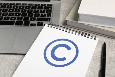 Image of License. Notebook with copyright symbol, pen and laptop on grey textured table, closeup