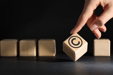 Image of License. Woman choosing wooden cube with copyright symbol on black background, closeup