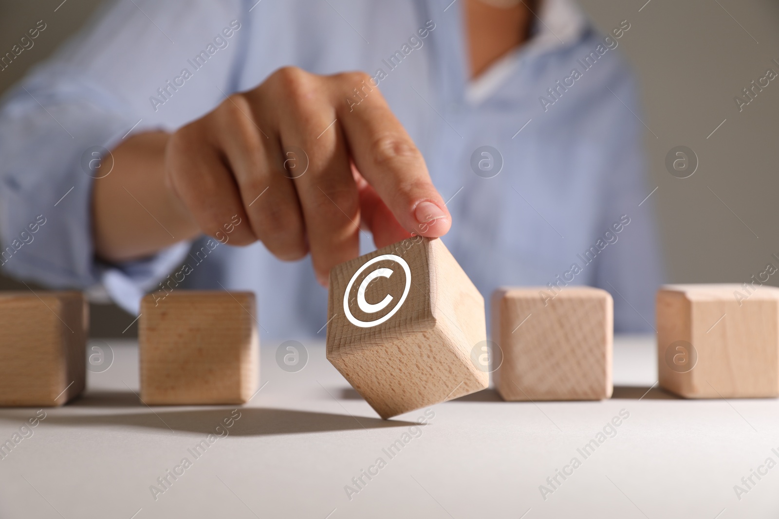 Image of License. Man choosing wooden cube with copyright symbol at table, closeup