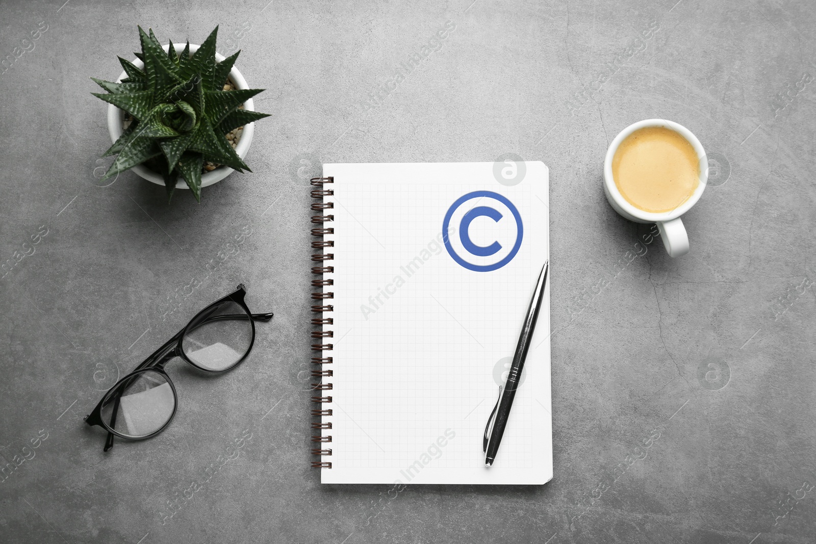 Image of License. Notebook with copyright symbol, pen, coffee, eyeglasses and plant on grey textured table, flat lay