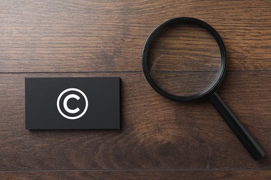 Image of License. Business card with copyright symbol and magnifying glass on wooden table, top view