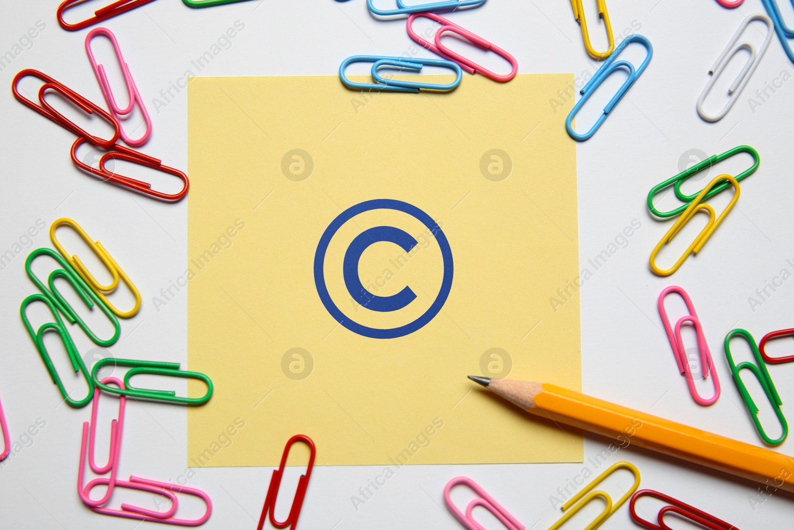 Image of License. Note with copyright symbol, paper clips and pencil on white background, top view