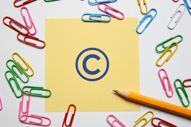 Image of License. Note with copyright symbol, paper clips and pencil on white background, top view