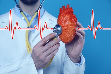 Cardiology. Doctor holding anatomical model of heart and stethoscope on blue background, closeup. Red heartbeat line