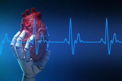 Image of Cardiology. Robot hand holding anatomical model of heart on gradient background. Blue heartbeat line