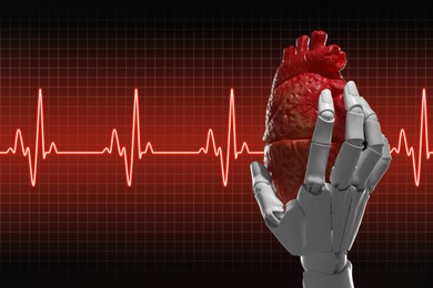 Cardiology. Robot hand holding anatomical model of heart on gradient background. Red heartbeat line