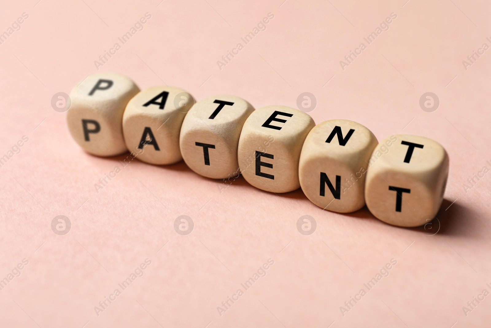 Image of License. Word Patent made of wooden cubes with letters on pink background, closeup