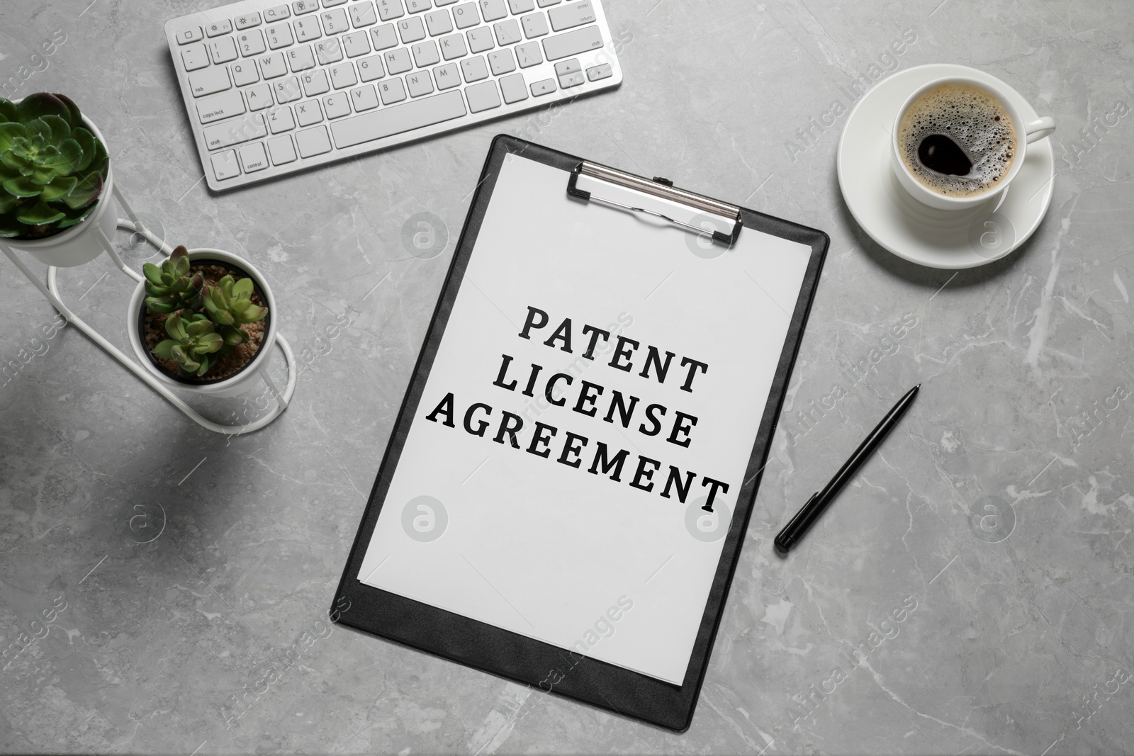 Image of Paper with Patent License Agreement text, pen, coffee and computer keyboard on grey table, top view