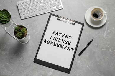 Image of Paper with Patent License Agreement text, pen, coffee and computer keyboard on grey table, top view