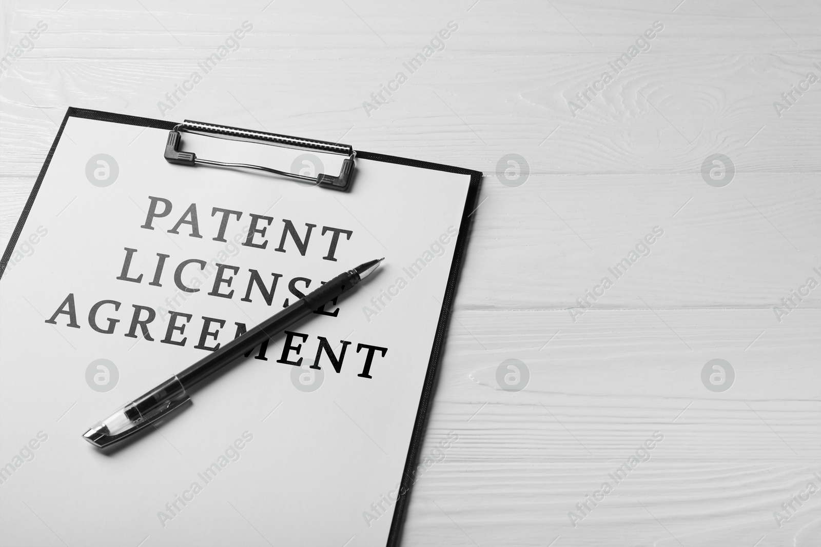 Image of Paper with Patent License Agreement text and pen on white wooden table, closeup