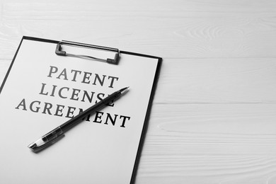 Image of Paper with Patent License Agreement text and pen on white wooden table, closeup