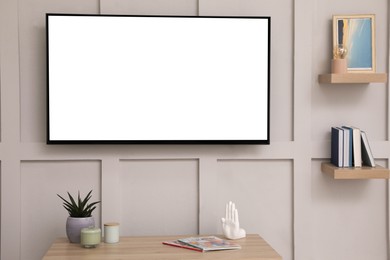 Tv set with white screen mounted on wall in room. Mockup for design