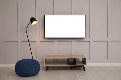 Image of Tv set with white screen mounted on wall in room. Mockup for design