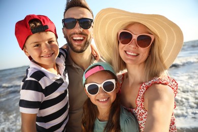 Photo of Happy family taking selfie on beach near sea. Summer vacation