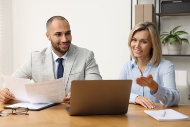 Photo of Coworkers with laptop working together in office