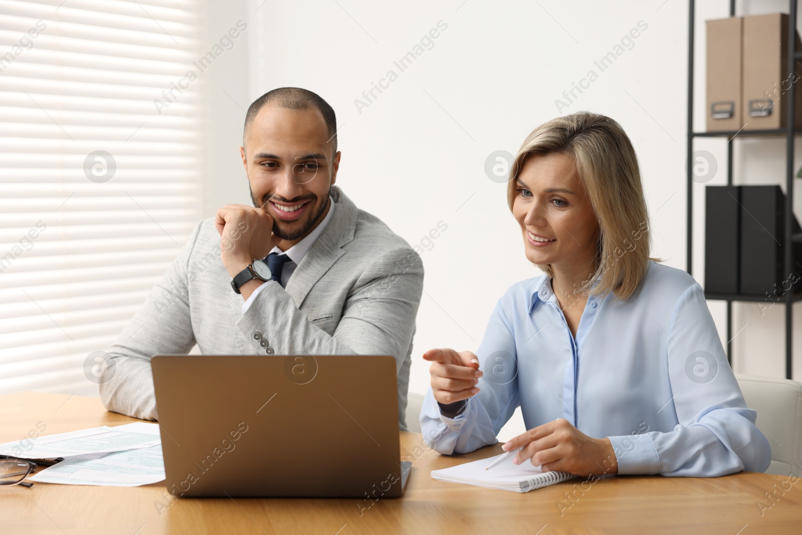 Photo of Coworkers with laptop working together in office