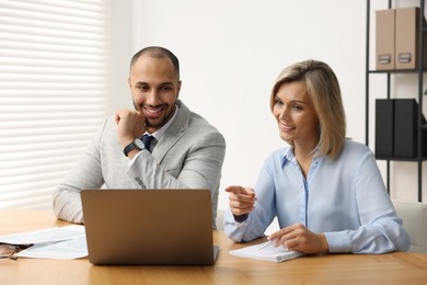 Coworkers with laptop working together in office