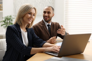 Photo of Coworkers with laptop working together in office