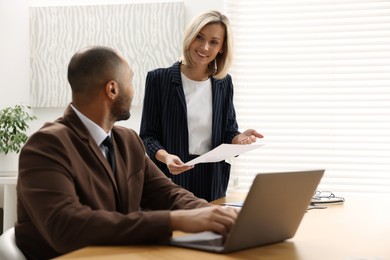 Photo of Coworkers working together at table in office