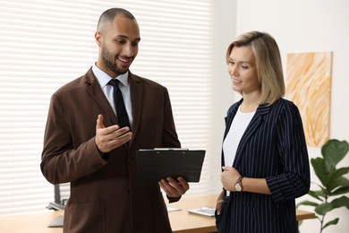 Photo of Coworkers with clipboard working together in office