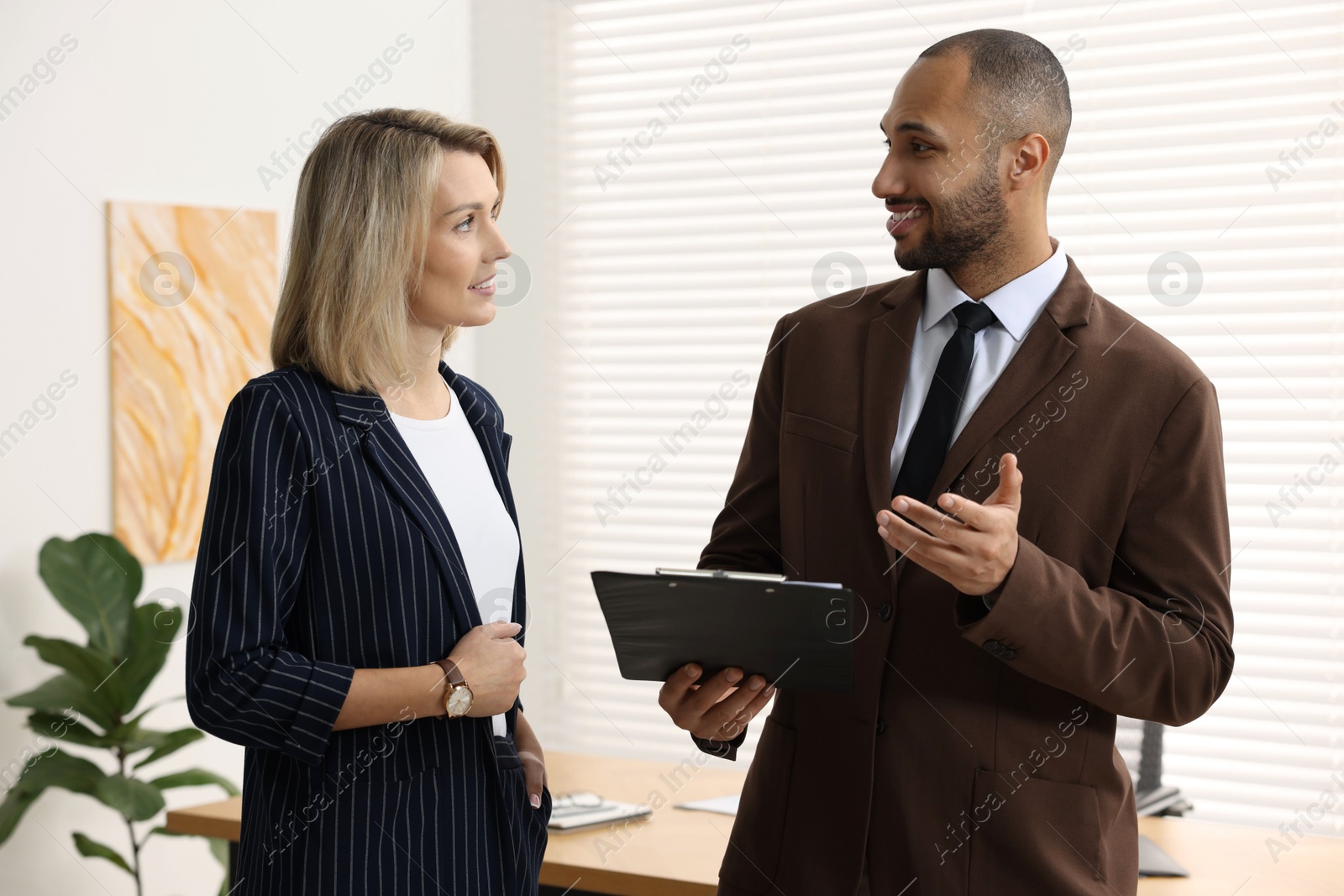 Photo of Coworkers with clipboard working together in office