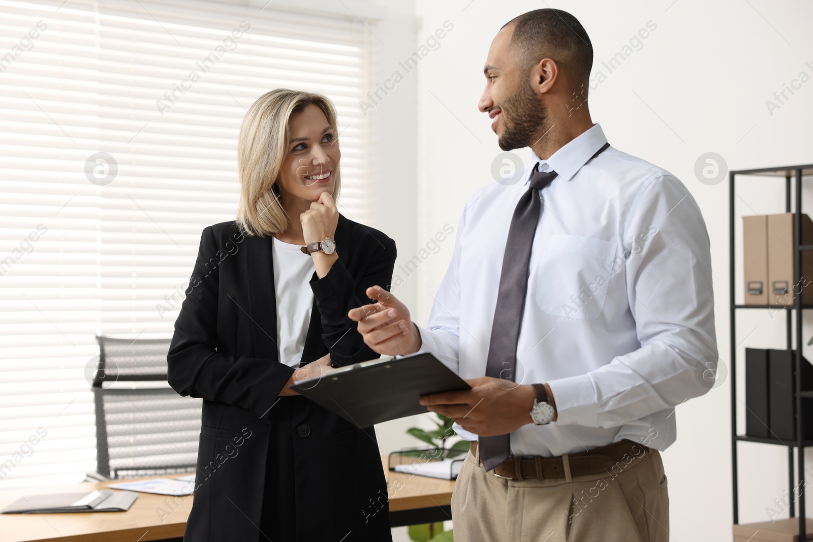 Photo of Coworkers with clipboard working together in office