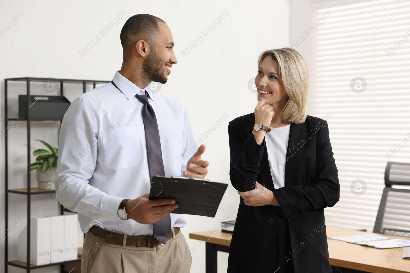 Photo of Coworkers with clipboard working together in office