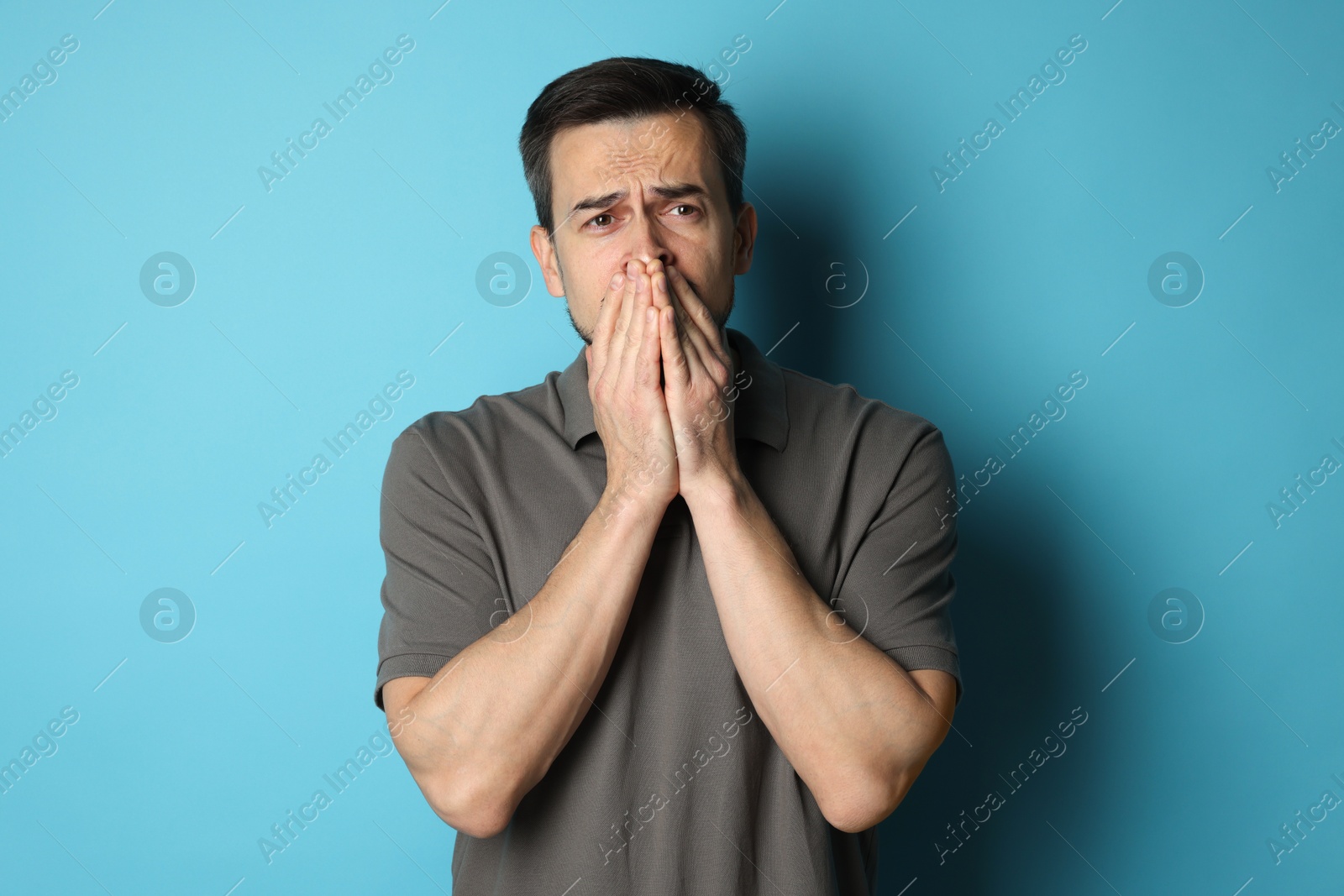 Photo of Sad man crying on light blue background