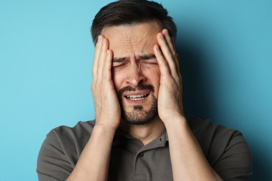 Photo of Sad man crying on light blue background