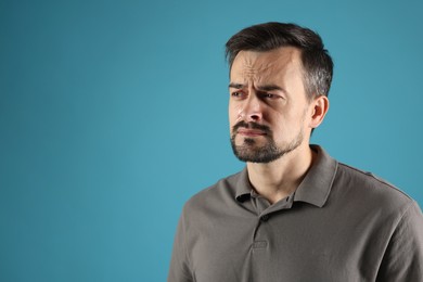 Photo of Sad man crying on light blue background, space for text