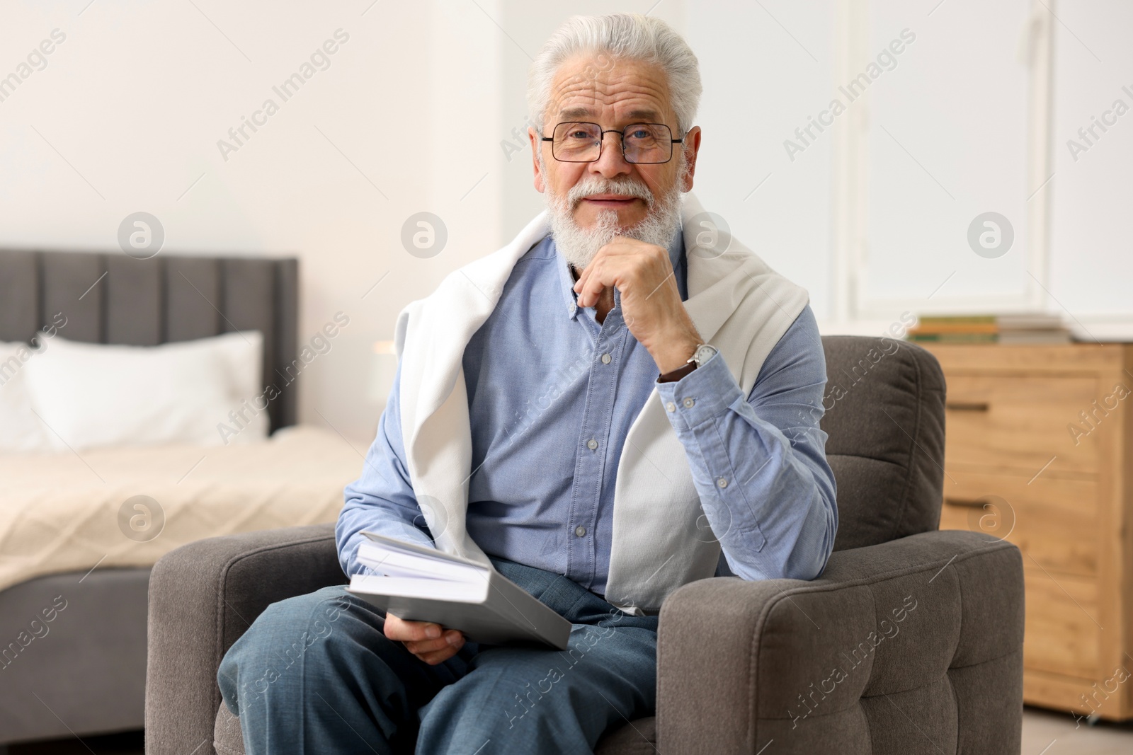 Photo of Handsome bearded man with book in armchair at home